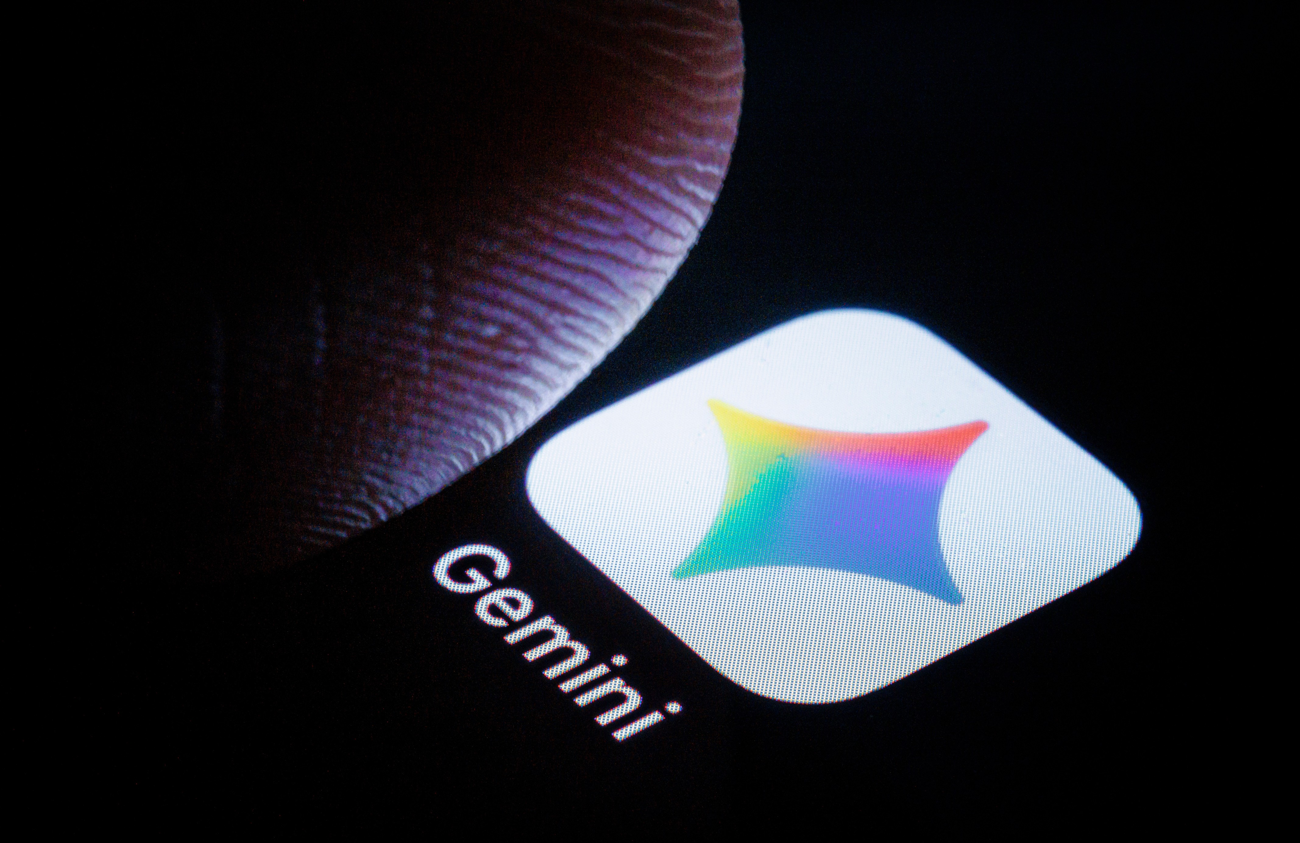 Um dedo humano toca a tela escura de um dispositivo, exibindo o ícone do aplicativo Gemini com um logotipo colorido e o nome Gemini em branco