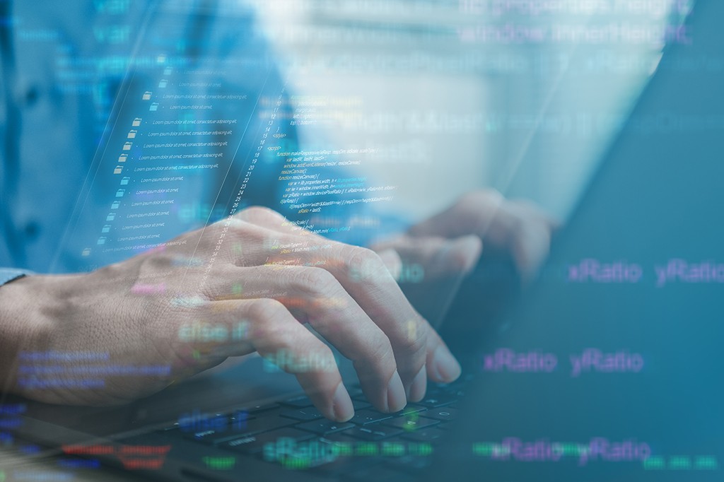 Mãos de uma pessoa digitando em um teclado de notebook, com sobreposição de códigos de programação em tons de azul e verde, criando um efeito futurista